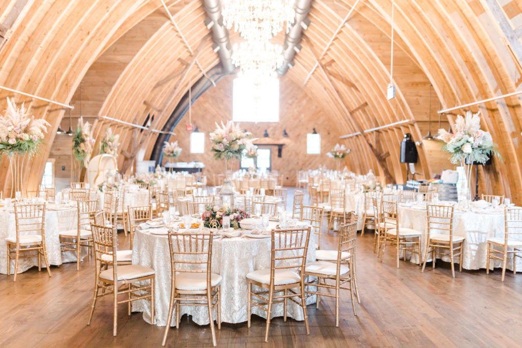 Round reception tables with white linens and elevated flower arrangements at Sweeney Barn in Manassas, VA