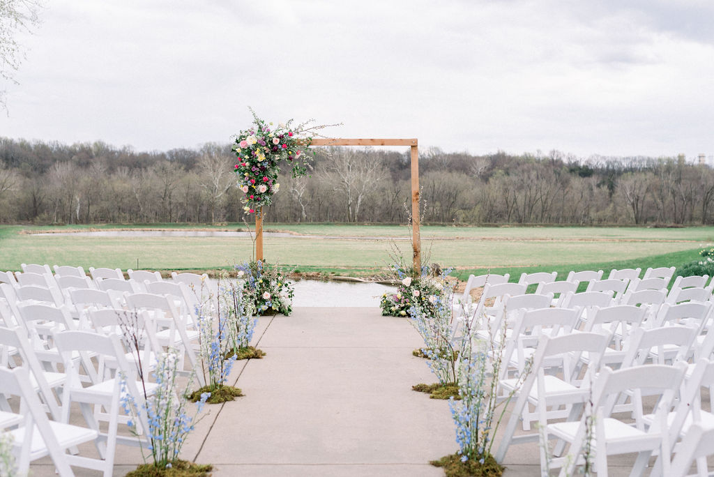 White folding ceremony chairs with flower aisle arrangements at Riverside on the Potomac in Leesburg, VA
