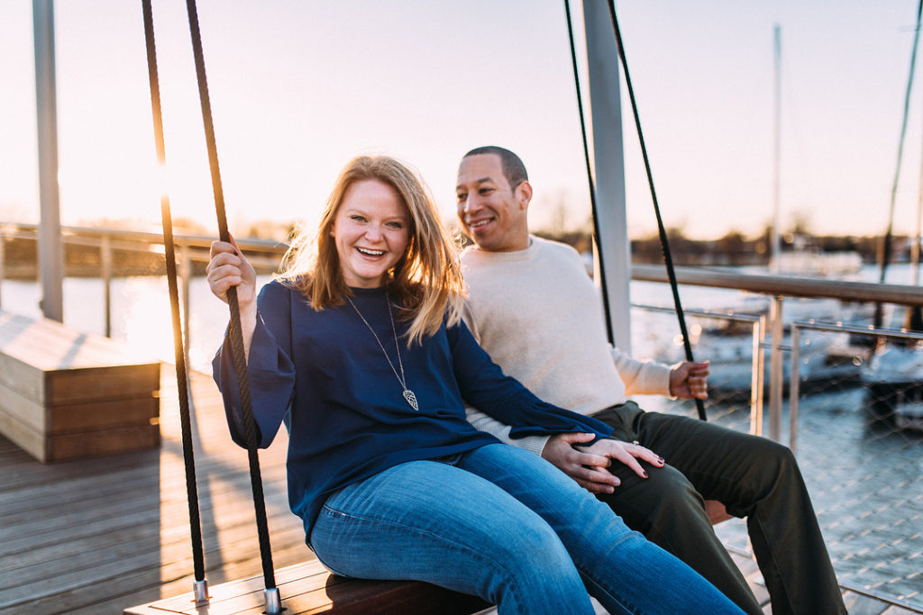 Couple sitting on swing at the Wharf in Washington, DC taking engagement photos