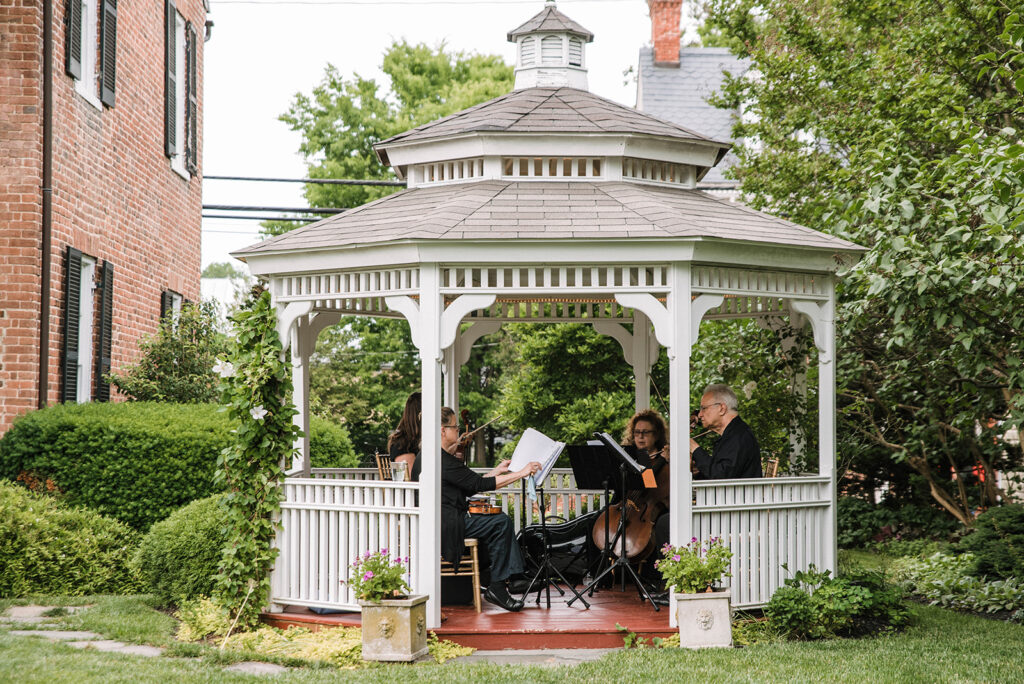 Wedding string quartet playing in white gazebo during cocktail hour at Birkby House